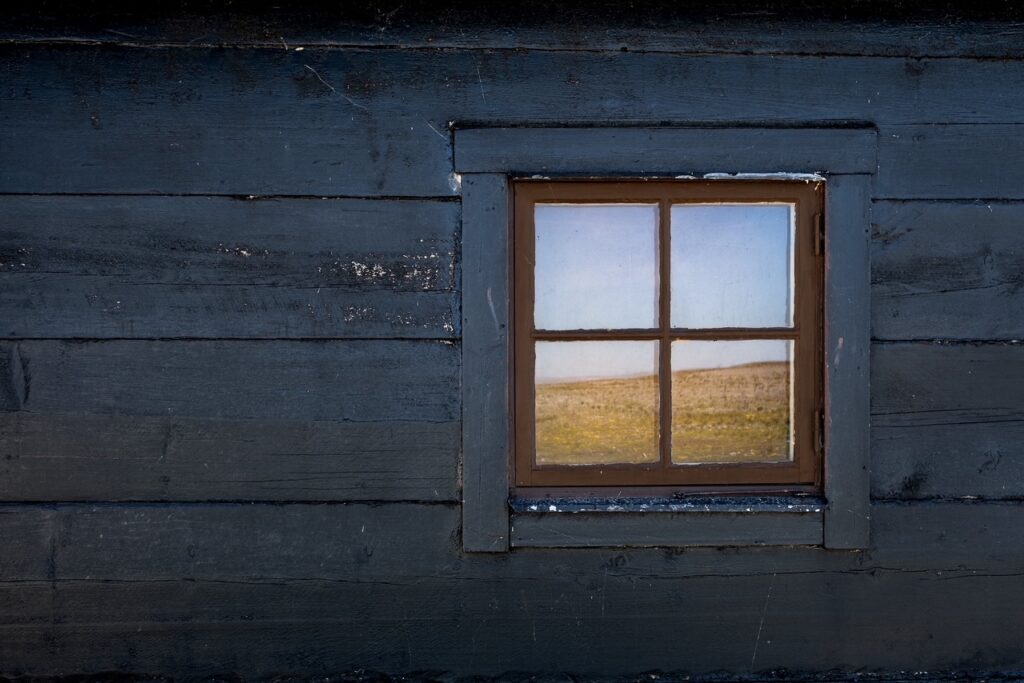 Ett foto på en fasad med ett fönster där landskapet bakom speglas. Bilden är från Thomas Hultgrens fotoutställning på Bellonis galleri.